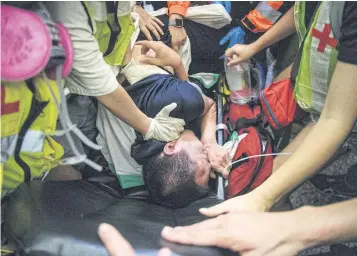  ?? AFP ?? An injured man who was suspected by protesters of being a Chinese spy is taken away by paramedics at Hong Kong’s internatio­nal airport early yesterday.