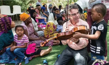  ?? JAG GUNDU/TORONTO SYMPHONY ORCHESTRA ?? Violinist James Wallenberg of the Toronto Symphony Orchestra visits with children as part of the Save a Child’s Heart program in Israel.