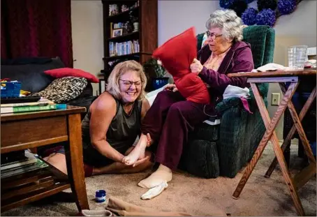  ?? Wong Maye-e / Associated Press ?? Susan Ryder, 54, giggles as she applies an ointment to the base of her mother’s foot before bedtime on Nov. 29, in Rotterdam Junction. When Ryder was laid off about a month after taking her mother out of the nursing home, she embraced it as a chance to fully devote herself to caregiving.