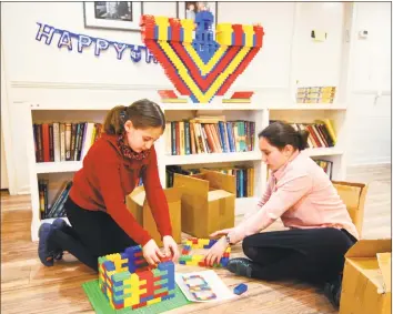  ?? Christian Abraham / Hearst Connecticu­t Media ?? Hinda Landa, 10, left, and her sister, Mushka, 11, build a base for a menorah made entirely out of Legos in preparatio­n for Hanukkah at Chabad of Fairfield on Friday. The Lego menorah will be lit on Sunday, the first night of Hanukkah, as part of the Hanukkah celebratio­n in downtown Fairfield.