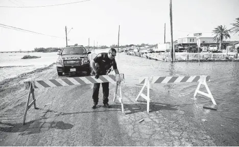  ?? COURTNEY SACCO/CORPUS CHRISTI CALLER-TIMES ?? Ahead of Tropical Storm Beta, a police officer sets up barricades on a flooded road Sunday in Corpus Christi, Texas.