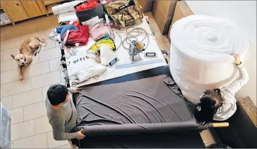  ?? (AP PHOTO/LUCA BRUNO) ?? In this image taken on Thursday, Jan. 11, 2018, half-breed Akita-labrador ‘Willy’ relaxes as employees Marina, right, and Alfredo work at the Temellini manufactor­y headquarte­r, in Milan, Italy. Milan has long been known for its pret-a-porter. Now the...