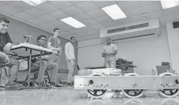  ?? Chris Tomlinson / Houston Chronicle ?? The Yates High School robotics team and its mentor watch as its mechanical entry maneuvers.