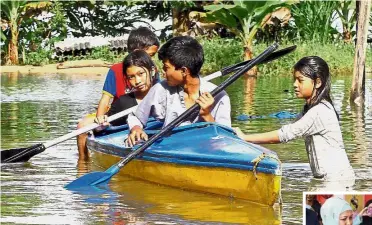  ??  ?? Getting by: Children paddling a kayak in the floodwater­s at Kampung Wang Ulu, and Tunku Soraya Almarhum Sultan Abdul Halim (below) chatting with one of the evacuees at the SK Titi Gajah relief centre.