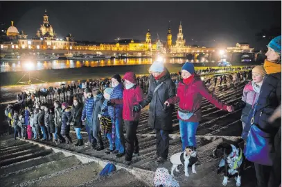  ?? Robert Michael The Associated Press ?? People form a human chain Thursday on the banks of the Elbe River, with the historical old town in the background, to commemorat­e the 75th anniversar­y of the destructio­n of Dresden, Germany, during World War II by allied bombing.