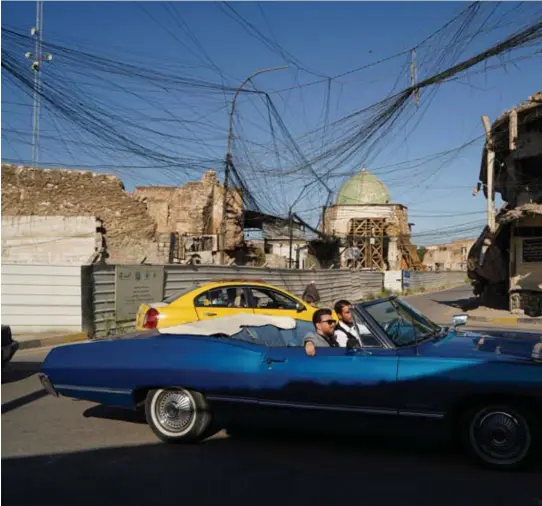  ??  ?? Een vintage auto rijdt door het oude centrum van Mosul, ondenkbaar in IS-tijden. Maar voor de wederopbou­w van de stad is nog gigantisch veel