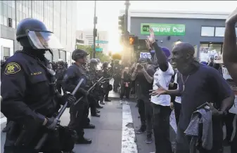  ?? Paul Kuroda / Special to The Chronicle ?? A crowd in Oakland confronts a police line at the Police Department building as they protest the killing of George Floyd by officers in Minneapoli­s. Hundreds also protested in San Jose.