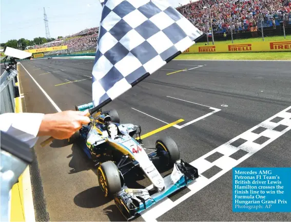  ?? Photograph: AP ?? Mercedes AMG Petronas F1 Team’s British driver Lewis Hamilton crosses the finish line to win the Formula One Hungarian Grand Prix