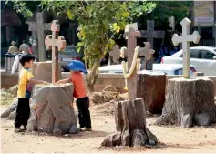  ?? — PTI ?? Children play near symbolic crosses fixed on tree trunks during a day-long protest against the building of a steel flyover in Bengaluru on Sunday.
