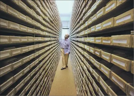  ?? Michael Probst Associated Press ?? I N THIS 2008 photo, Jewish genealogy researcher Gary Mokotoff of the United States checks name registers at a Holocaust center in Bad Arolsen, Germany. Germany has made greater efforts in recent decades to educate its citizens on the horrors of that genocide.