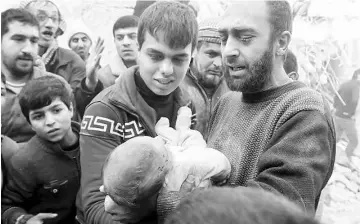  ??  ?? A man holds the body of a dead child after airstrikes by pro-Syrian government forces in the rebel held al-Qaterji neighbourh­ood of Aleppo, Syria. — Reuters photo