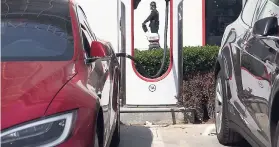  ?? AP ?? In this Friday, April 14, 2017, file photo, a security guard moves past an electric vehicle charging station in Beijing. Momentum is building worldwide for electric cars thanks to rising government fuel economy standards and climate concerns.