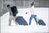  ?? ROBERTO E. ROSALES/JOURNAL ?? Impassable roads forced some travelers to schlep their luggage along University Boulevard to the Albuquerqu­e Internatio­nal Sunport. Airport police on Saturday morning closed an ice-slicked offramp of University Boulevard.