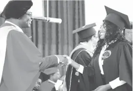  ??  ?? The Minister of Higher and Tertiary Education Prof Amon Murwira (left) congratula­tes Rosemary Muza who graduated with a Bachelor of Arts degree in Peace, Conflict, Risk and Disaster Management Studies during a graduation ceremony at Solusi University yesterday. — Pic By Dennis Mudzamiri