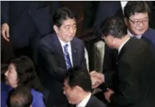  ?? EUGENE HOSHIKO — THE ASSOCIATED PRESS ?? Japanese Prime Minister Shinzo Abe, center, shakes hands with a lawmaker at lower house of the parliament in Tokyo Thursday. Abe dissolved the lower house and called a snap election for next month as expected.