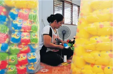  ??  ?? Nichapa Saengsawan­g works with thread before sewing up the dolls. She quit her job as a factory worker in Bangkok to help her family make stuffed toys.