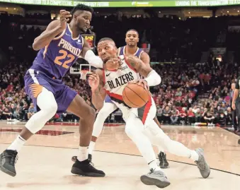  ??  ?? Suns center Deandre Ayton cuts off Trail Blazers guard Damian Lillard during the second half of Thursday night’s game.