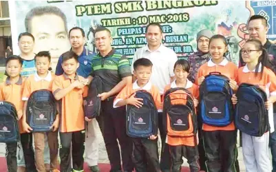  ??  ?? AZMAN menyampaik­an bantuan persekolah­an kepada murid-murid yang memerlukan.