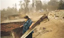  ?? MATIAS DELACROIX, AP ?? A woman clears debris from a landscape of charred remains in Santa Ana, Chile, on Saturday.