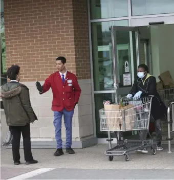  ?? NICOLAUS CZARNECKI / HERALD STAFF FILE ?? FRONT-LINE EXPOSURE: Shoppers at Market Basket line up to enter the store, with clerks and security standing by on the front lines, as limits were put in place for the amount of people allowed in at once in Chelsea on April 2.