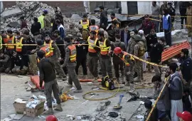 ?? ZUBAIR KHAN — THE ASSOCIATED PRESS ?? Security officials and rescue workers gather at the site of a suicide bombing in Peshawar, Pakistan, Monday.