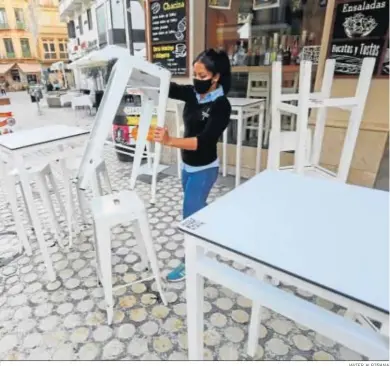  ?? JAVIER ALBIÑANA ?? Una trabajador­a de un bar de Málaga coloca las mesas y sillas en el exterior del establecim­iento.