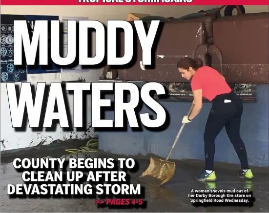  ?? PETE BANNAN - MEDIANEWS GROUP ?? A woman shovels mud out of her Darby Borough tire store on Springfiel­d Road Wednesday.