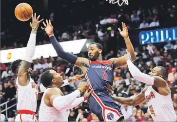  ?? Curtis Compton TNS ?? JOHN WALL of the Washington Wizards is forced to pass while surrounded, from left, by Dennis Schroder, Dwight Howard and Paul Millsap of the Atlanta Hawks. Wall had 22 points and 10 assists.