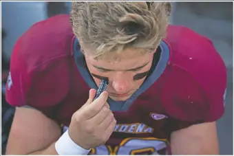  ?? (AP/Jae C. Hong) ?? El Modena center Jack Stein applies black stripes before the team’s football game with El Dorado in Orange, Calif.