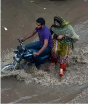  ?? — AFP ?? Pakistani residents travel through flood waters following heavy rain in Lahore on Thursday.