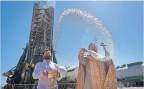  ?? DMITRI LOVETSKY, AP ?? An Orthodox priest conducts a blessing service in front of the Soyuz FG rocket at the Russian leased Baikonur cosmodrome in Kazakhstan on Thursday. The new Soyuz mission to the Internatio­nal Space Station is scheduled for Friday, carrying U.S....