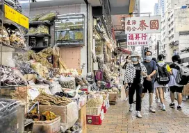  ?? —PHOTOS BY AFP ?? FOOD MART People walk past a shop that sells sharks fin and other seafood in Hong Kong.