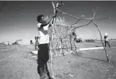  ?? ASHRAF SHAZLY/GETTY-AFP ?? An Ethiopian refugee, who fled fighting in Tigray, builds a shelter Sunday at a border reception center in Sudan.