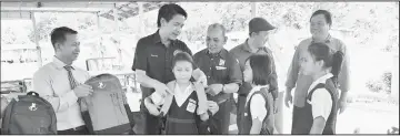  ??  ?? Dennis (second left) presents a school bag to a pupil.