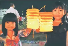  ??  ?? Children carry traditiona­l paper lanterns into the town square.