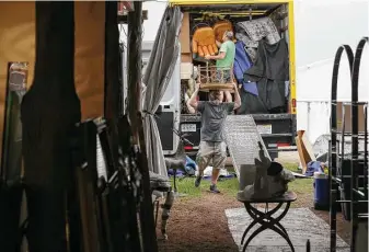  ?? Godofredo A. Vásquez / Staff photograph­er ?? Chris Gibbie, center, and his husband, Tim Mashburn, unload furniture to get their Marburger Farm Antique Show booth ready. Gibbie and Mashburn have been taken part the past nine years.