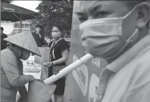  ?? MANAN VATSYAYANA / AGENCE FRANCE-PRESSE ?? A resident wearing a face mask fills a paper bag with free rice in Hanoi on Saturday. Vietnamese have been restrictin­g their movements as a preventive measure against the spread of the novel coronaviru­s.