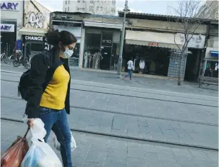  ?? (Yossi Zamir/Flash90) ?? PEOPLE WEAR face masks in the city center of Jerusalem yesterday.