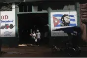  ?? ARIEL LEY — THE ASSOCIATED PRESS ?? Shoppers exit a state-run agro-market, where a mural of Fidel Castro adorns the facade, in Havana, Cuba, Thursday, March 7.