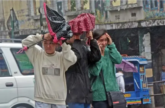  ?? Photo by Milo Brioso ?? WATERPROOF. Baguio locals close their umbrella so as not to be blown away by gust of wind brought by tropical storm "Isang" which enhances the southwest monsoon.