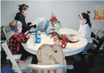  ?? NATHAN DENETTE THE CANADIAN PRESS ?? Kristy Denette, back left, tries to work from home as her two children Maverick, five, and Peyton, seven, do online schooling at the kitchen table in their home in Mississaug­a.