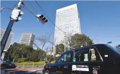  ?? — AFP ?? A taxi passes the headquarte­rs of Japan’s Toshiba in Tokyo.