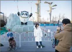  ?? (AP/Mark Schiefelbe­in) ?? A woman poses for a photo Jan. 12 with a statue of the Winter Olympics mascot Bing Dwen Dwen in Beijing.