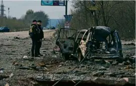  ?? SERGEY BOBOK/AFP VIA GETTY IMAGES ?? Police examined a destroyed car on Saturday in Kharkiv after a barrage of missiles hit the city.