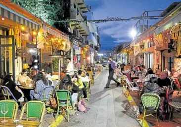  ??  ?? BACK IN BUSINESS People eat at a restaurant in the Israeli coastal city of Tel Aviv on March 7 after authoritie­s reopened restaurant­s, bars and cafes to vaccinated ‘green pass’ holders.