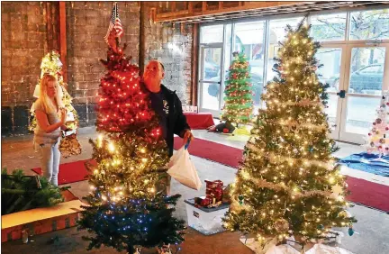  ?? DIGITAL FIRST MEDIA FILE PHOTO ?? Cliff Booz tops a patriotic-themed Christmas tree with an American flag Thursday, Nov. 19, 2015, in a display area in the Hager & Schultz Building on West Main Street that has been set aside for the fifth annual Lansdale Christmas Tree Display. Booz and Kelley Kash, at left, were trimming the tree that represents Lansdale VFW Post 32, where they are both members.