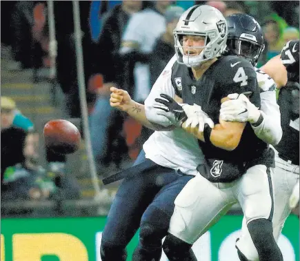  ?? Heidi Fang ?? Las Vegas Review-journal @Heidifang Raiders quarterbac­k Derek Carr (4) is sacked by Seattle Seahawks defensive end Frank Clark, who caused a fumble. Carr was sacked six times and fumbled twice in the Raiders’ 27-3 loss to the Seahawks at Wembley Stadium in London.