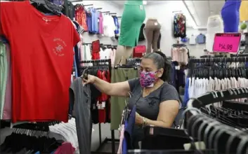  ?? Kathy Willens/Associated Press ?? A woman shops Monday in a Mini Max store in Brooklyn, N.Y., as retail stores were allowed to resume sales with some restrictio­ns under Phase 1 of the state's reopening plan.