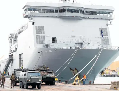  ?? Photos / Duncan Brown ?? HMNZS Canterbury (above) brought New Zealand and US troops and vehicles into Port of Napier for Exercise Alam Alpha at various locations around Hawke's Bay. Members of the Royal New Zealand Air Force's 6 Squadron (left) prepare to secure the rope of the NH90 helicopter to a box of supplies.