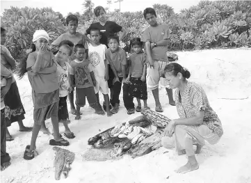  ??  ?? Gisela buying fish on the beach.